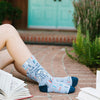 A woman reading a book while wearing Fuck Off, I'm Reading socks