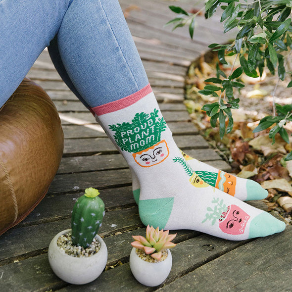 A woman wearing fun socks that say, “Proud Plant Mom”