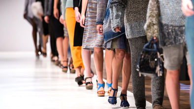 a close up of women walking in a line on a fashion show cat walk