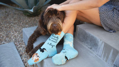 A woman wearing fun socks, sitting with a dog