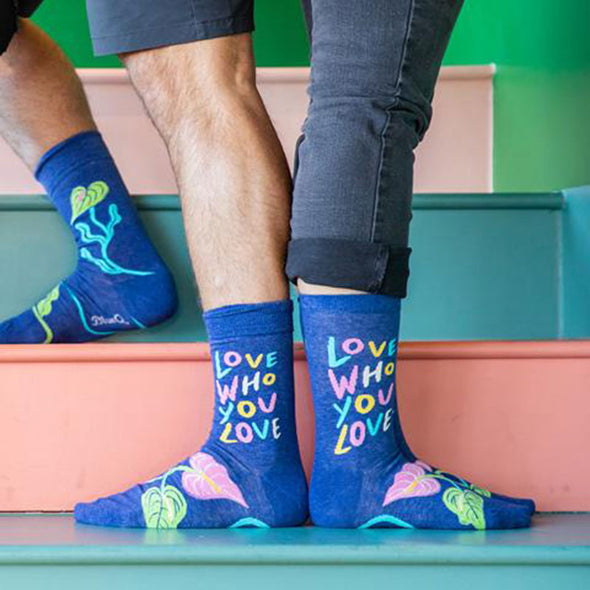 man and woman standing and wearing fun socks that say "love who you love"