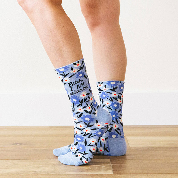 A woman wearing funny floral socks that say, “Bitch, I AM relaxed”