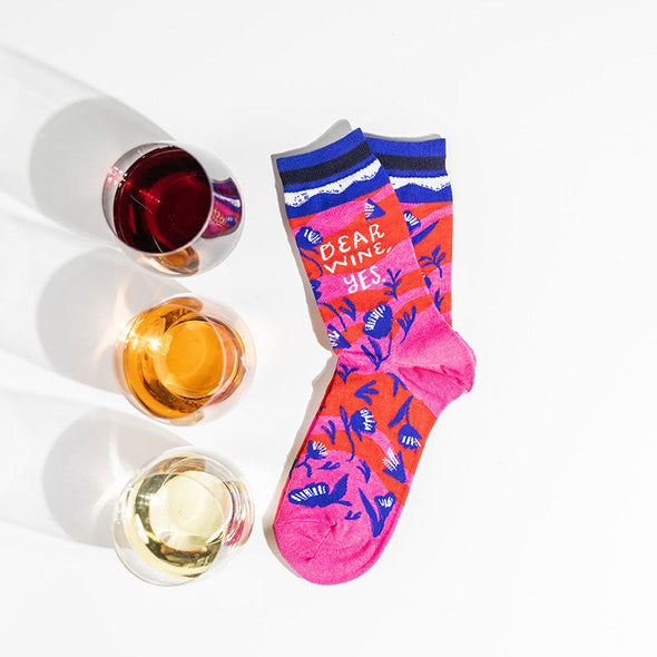 three glasses of wine next to cute women's socks that say, "dear wine, yes"