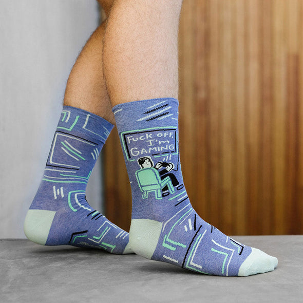A man wearing funny socks that say 'fuck off, I'm gaming'