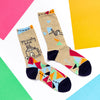 Flat lay view of “crafty bitch” socks laying next to colorful construction paper