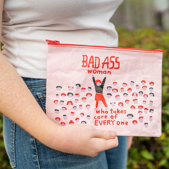 woman holding a zippered pouch that says, "bad ass woman who takes care of everyone"
