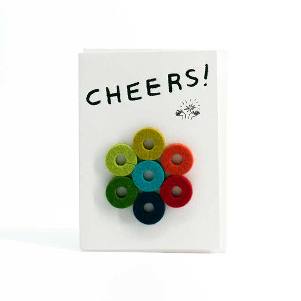 Colorful, round felt wine charms with a card that says “Cheers!”