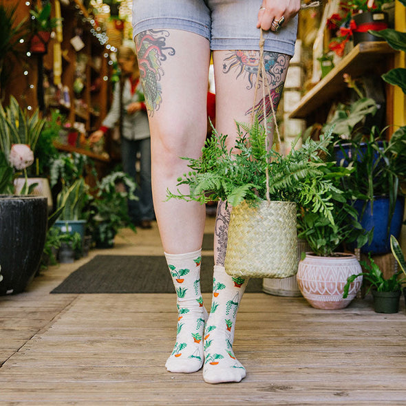 A woman wearing socks with a pattern of green potted plants