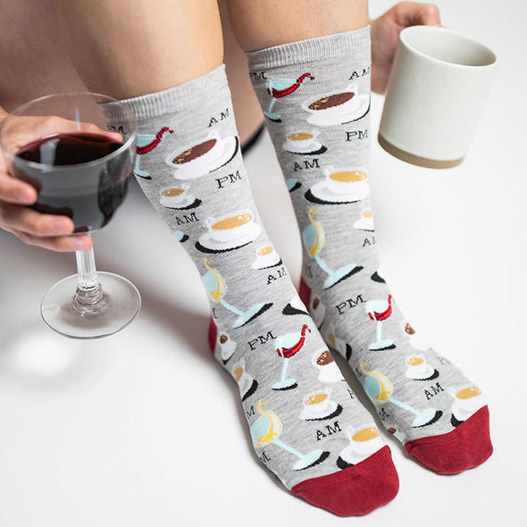 woman wearing funny socks with cups of coffee, glasses of wine and the words "am" and "pm"