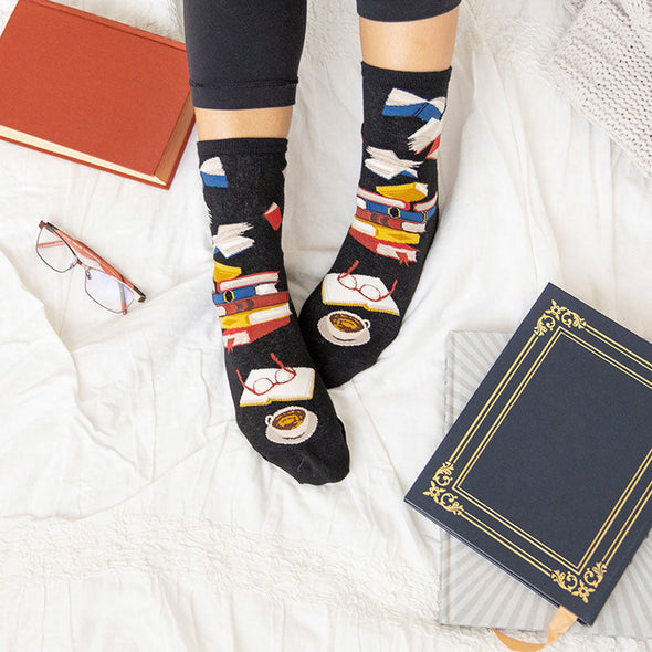A woman wearing novelty book socks for women while reading