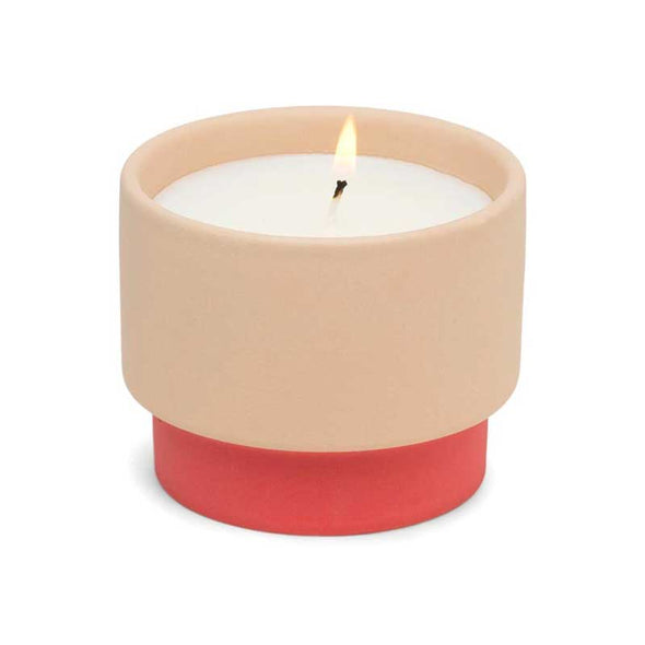 Scented candle in a textured ceramic vessel in coral and pink colors