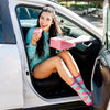 A woman sitting in her car eating donuts while wearing donut novelty socks 