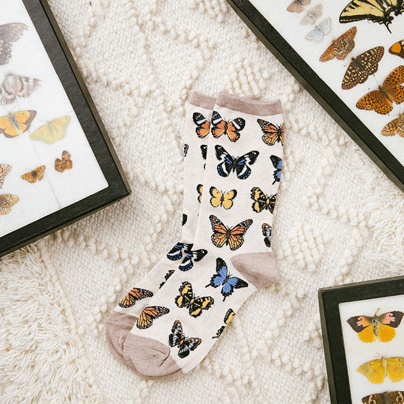Pretty butterfly socks laying flat next to framed butterfly artwork