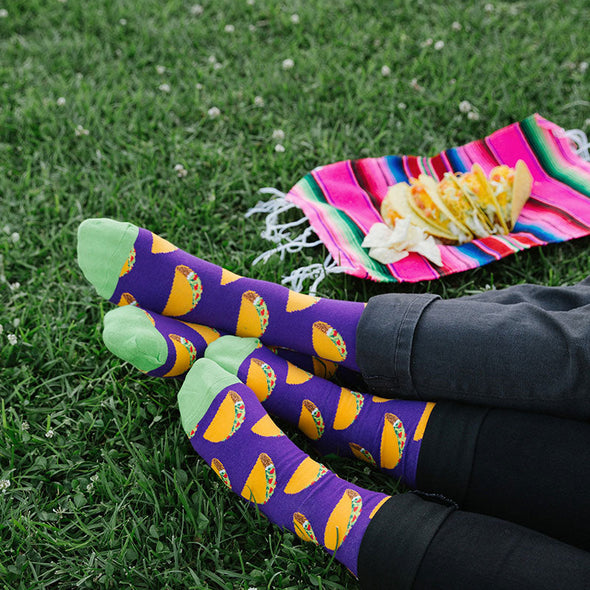 A man and a woman wearing matching taco socks while having a taco picnic