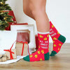 A woman wearing Christmas socks with gold jingle bells and the words, “All the jingle ladies” set against a red background