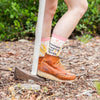 woman standing next to a sledgehammer, wearing boots and socks that say, "motherfucking girl power"
