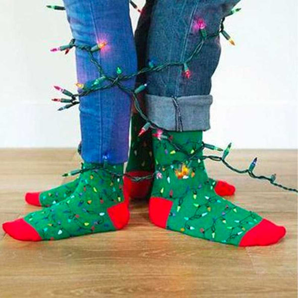 A man and a woman wearing fun Christmas lights holiday socks while tangled in Christmas lights