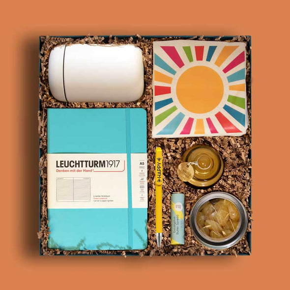 Upscale, curated gift box with lip balm, a travel mug, custom tote and more, all in sunshiny colors