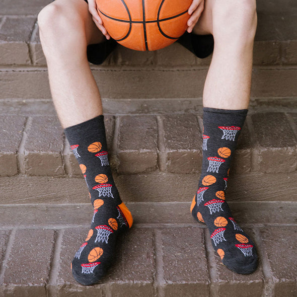 A man holding a basketball wearing XL socks with a pattern of a basketball about to go through the hoop