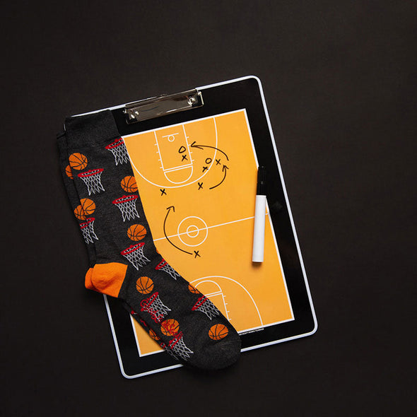 A marked-up basketball playsheet and fun men's XL socks with a pattern of a basketball about to go through the hoop