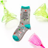 Funny 'I have mixed drinks about feelings' socks laying flat next to colorful margarita glasses