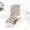 Women’s music socks in white with a pattern of sheet music and musical notes laying flat