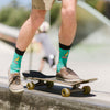 A man skateboarding while wearing funny novelty socks with a banana riding a skateboard and wearing sunglasses