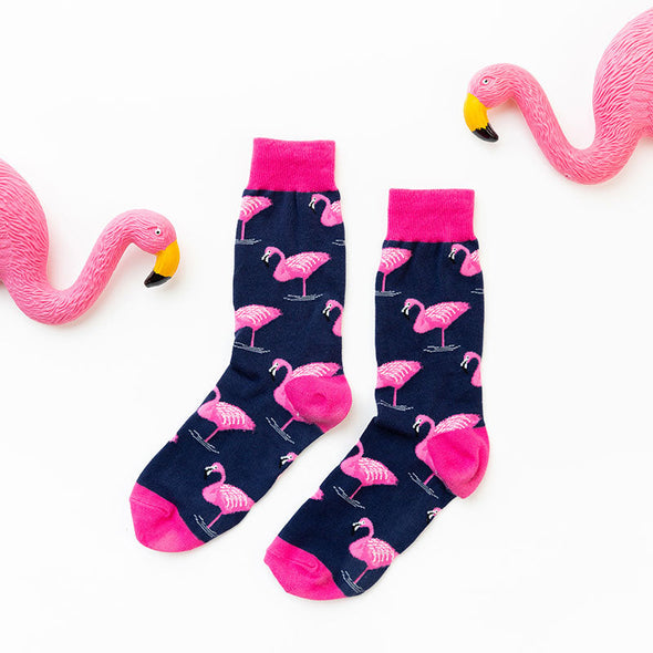 Novelty flamingo socks laying flat next to fun flamingo decorations