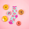 Fun donut novelty socks for women, in mint green, next to several donuts