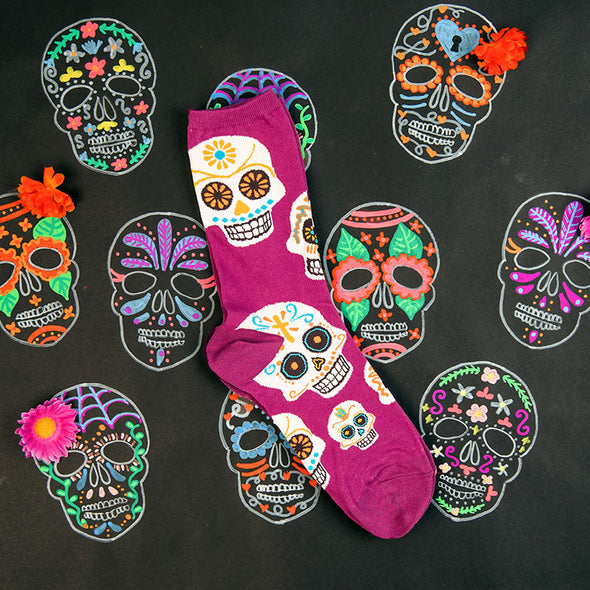 cute women's socks with a patter of sugar skulls, surrounded by drawings of sugar skulls