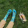 A man wearing sushi socks sitting on grass with sushi lunch