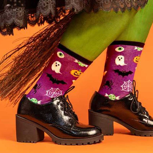 Fabulous witch wearing black heeled shoes and spooky, purple Halloween socks