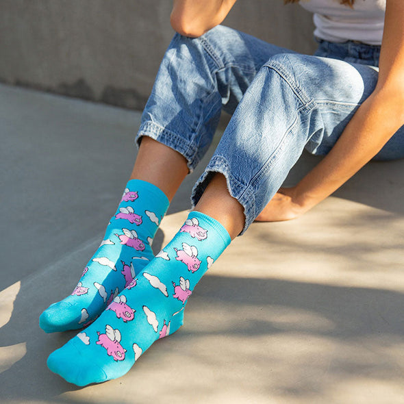 A woman wearing colorful flying pig animal socks by Socksmith in blue